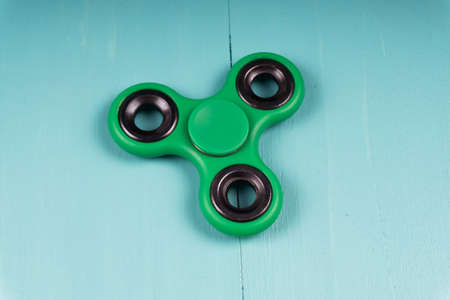 Fidget spinner stress relieving toy on blue wooden background.の写真素材