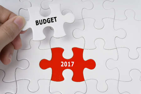 Hand holding piece of jigsaw puzzle with words Budget 2017.の写真素材
