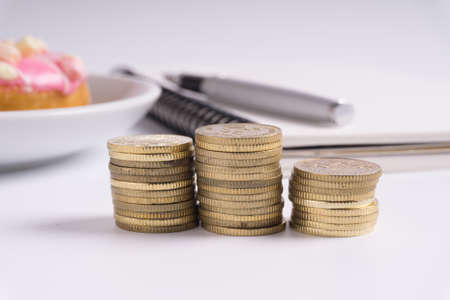 Coin stacked with notebook and donut on white background. Business and Financial concept.の写真素材