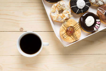 Cup with coffee and donuts on a wooden background.