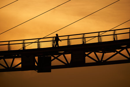 Silhouette person walking at bridge over sunset.の写真素材