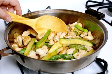 chicken and zucchini sauteeing in a frying panの写真素材