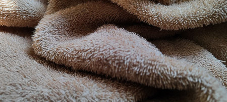 A high-resolution close-up of a beige towel, showing its soft and intricate texture details for...