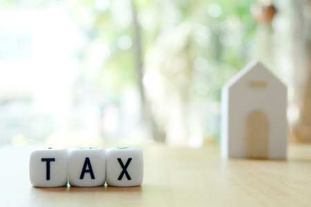 TAX cube with house model on wood table and bokeh backgroundの写真素材
