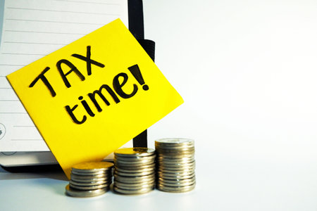 Tax time concept with stack of coins and yellow sticky note with text TAX TIMEの写真素材