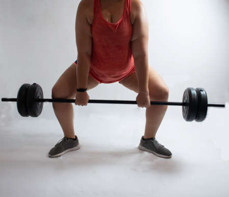 White woman performing barbell dead lift on a white backgroundの写真素材