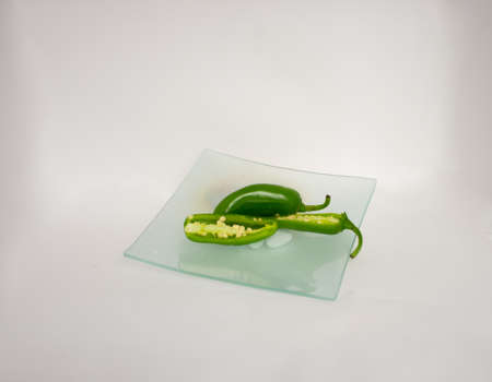 Green jalapeno chili in a transparent plate with its white background