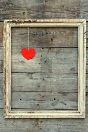Vintage wooden frame with red heart on a grunge background.  Love designの写真素材