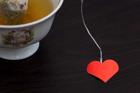 Cup of tea with heart shape on a black wooden table. Love designの写真素材