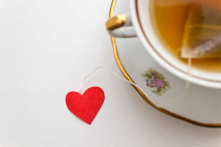 Cup of tea with heart shape. Vintage cup of tea and heart shape on a white tableの写真素材