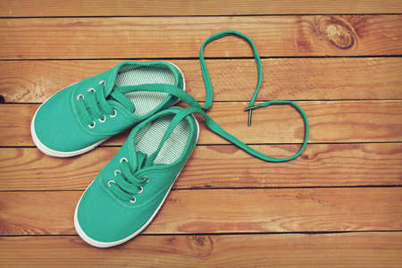 Top view of a pair of shoes with laces making heart shape on wooden floor. Heart made of shoelacesの写真素材