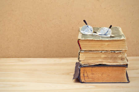 Vintage books. Stack of old books with glasses on top on wooden table. Good copy-spaceの写真素材