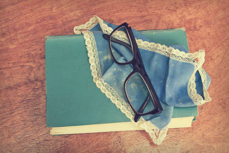 Old book and glasses. Vintage book, handkerchief and glasses on top on wooden table 