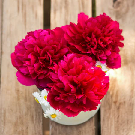 Red peonies in vase on wood background  Summer bouquet red peonies and white daisy on rustic table outdoorの写真素材