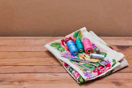 Background with sewing tools and colored thread. Sewing accessories. Scissors, bobbins with thread and needles on wooden tableの写真素材