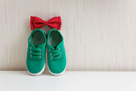 Bow tie and green shoes on background wall with wallpaper. Green sneakers and red bow tie with polka dotの写真素材
