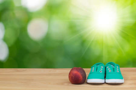 Sneakers and peach on foliage bokeh background. Health conceptの写真素材