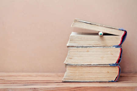 Stack of old books and pencil on wooden table