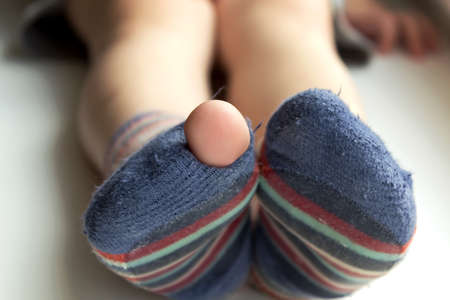 Worn  out socks. Worn socks with a hole and a finger sticking out of themの写真素材