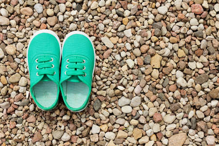 Green sneakers on a background of small stones. Pair of shoesの写真素材