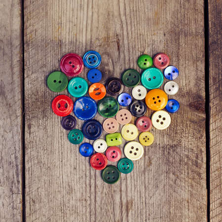 Vintage buttons in the shape of a heart on a wooden  background. Toned imageの写真素材
