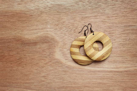 Fashion earrings on wooden surface. Wooden earringsの写真素材