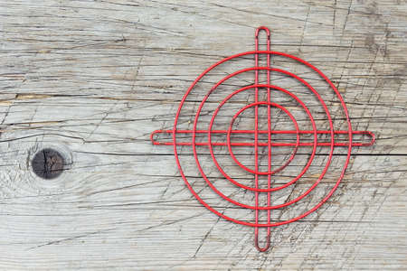 Red metallic crosshair on an old wooden surfaceの写真素材
