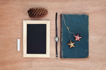 Vintage objects collection. Old book, christmas decorations, vintage clock, chalkboard, chalk, pine cones on a wooden background. Place for your text. Hipster lifestyleの写真素材