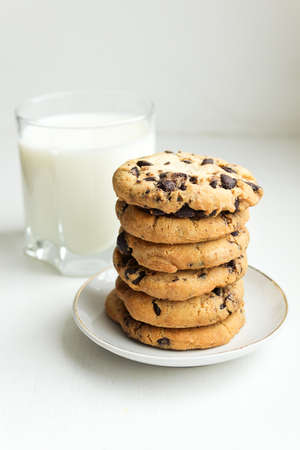 A stack of Biscuit cookies with chocolate chips and a glass of milkの写真素材