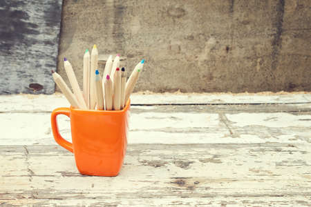 Color pencils in a orange cup. Back to school concept on grunge backgroundの写真素材