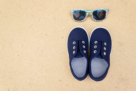 Blue sneakers and sunglasses. Summer holidays. Top view trendy shoes and glasses. Hipster set. Children theme. Space for textの写真素材