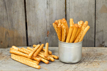 Tasty breadsticks grissini in iron cup. Food on wooden backgroundの写真素材