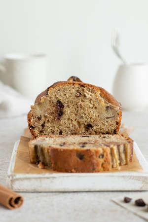 Banana bread with dark chocolate. Incision and piece of banana cake on the perchament. Cake...