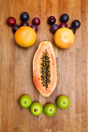 face made of fruits on wooden backgroundの写真素材