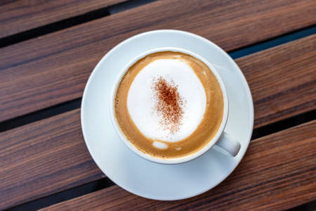 Cappuccino coffee with bubbles in wooden tray, black background.