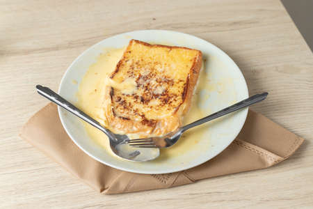 Toast on a white plate on a wooden table.