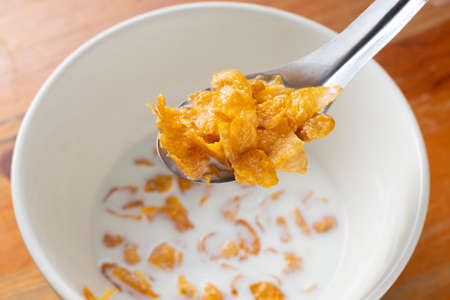 Bowl of cornflakes in milk on wood background from above.