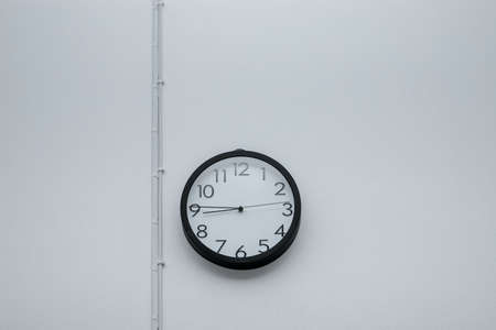 Black wall clock with white cementの写真素材