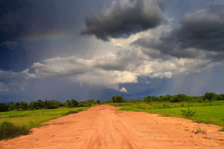 dirt road, cloudy sky and fieldの写真素材