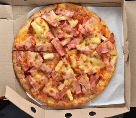 Pineapple and ham pizza in a cardboard box full.の写真素材