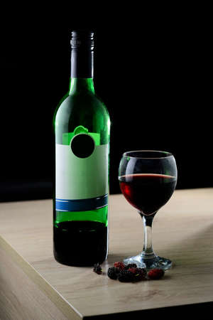 red wine in wine glass with green wine bottleの写真素材