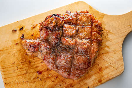 Pork steak cooked on a wooden cutting boardの写真素材