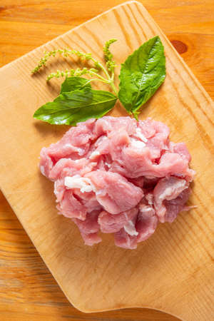 Raw pork minced pork on a wooden chopping board and basil leavesの写真素材