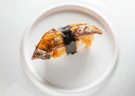 a piece of fish sushi on a white plateの写真素材