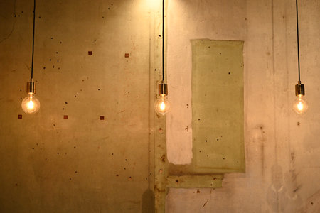 Orange hanging light bulb against old cement wall