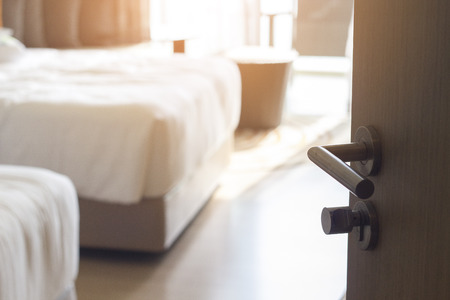 Opened door of hotel room in bedroom background , selective focus