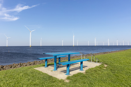 Benches on observation deck with windmills and sea at background