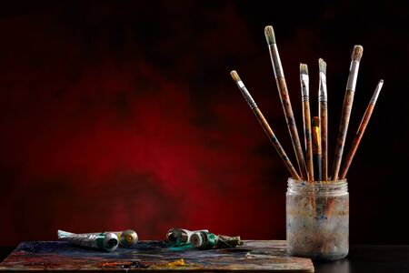Paint brushes with a palette on a colored background.