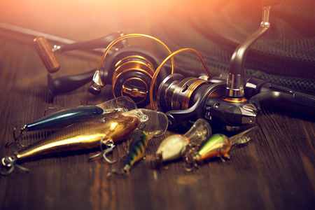 Fishing tackle - fishing spinning, hooks and lures on darken wooden background.の写真素材