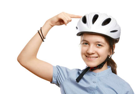 Young girl in a white bicycle helmet points to a helmet, isolated on white.の写真素材